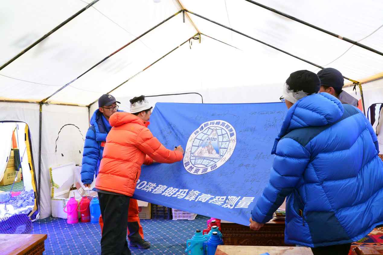 队员们在本次活动旗帜上签名留念。中国登山协会供图 卢明文摄